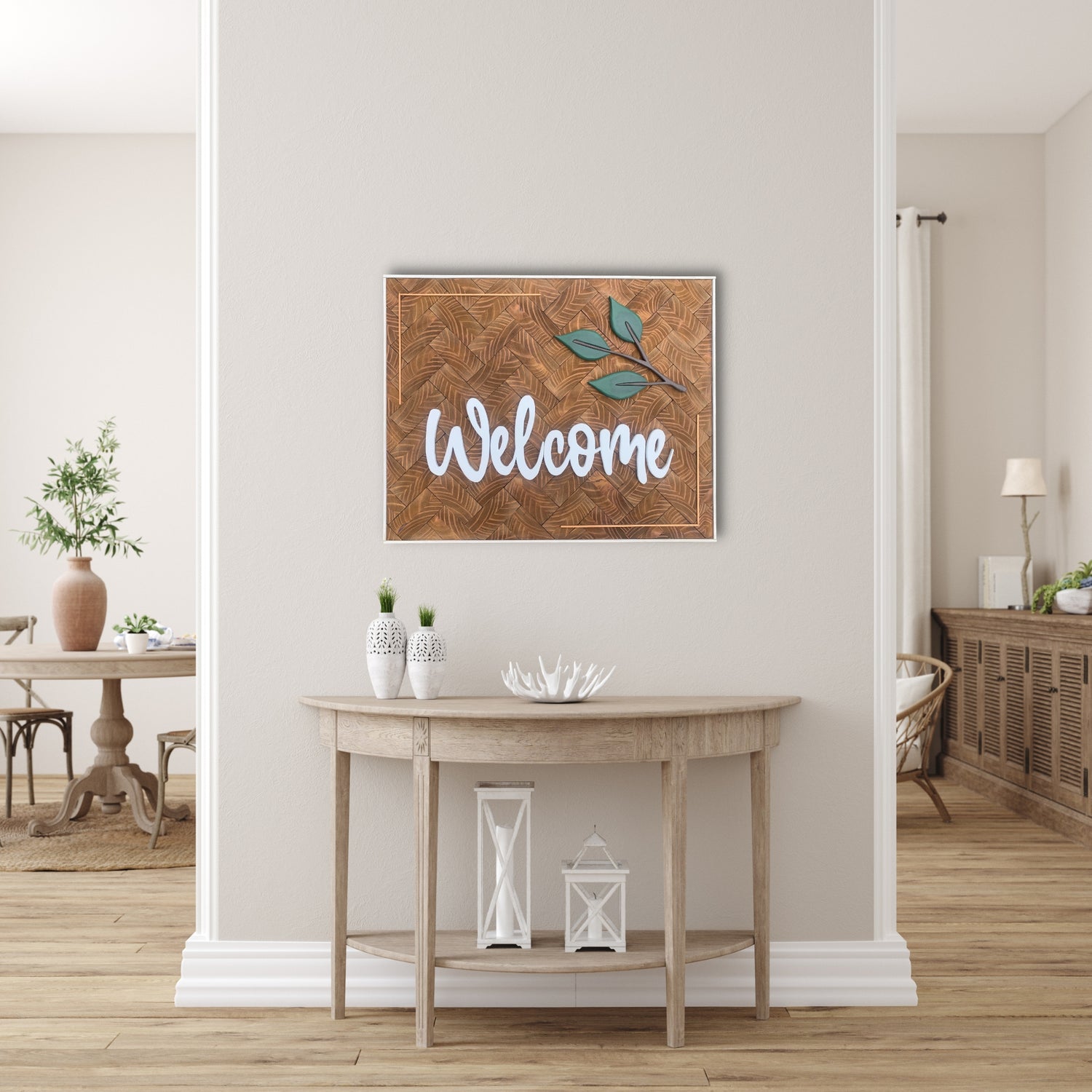 Custom wooden wall sign with the word “Welcome” in white script lettering, accented by green leaves and set against a carved hardwood background with a herringbone texture. Displayed in a light, neutral-toned entryway with rustic decor and natural wood furnishings.