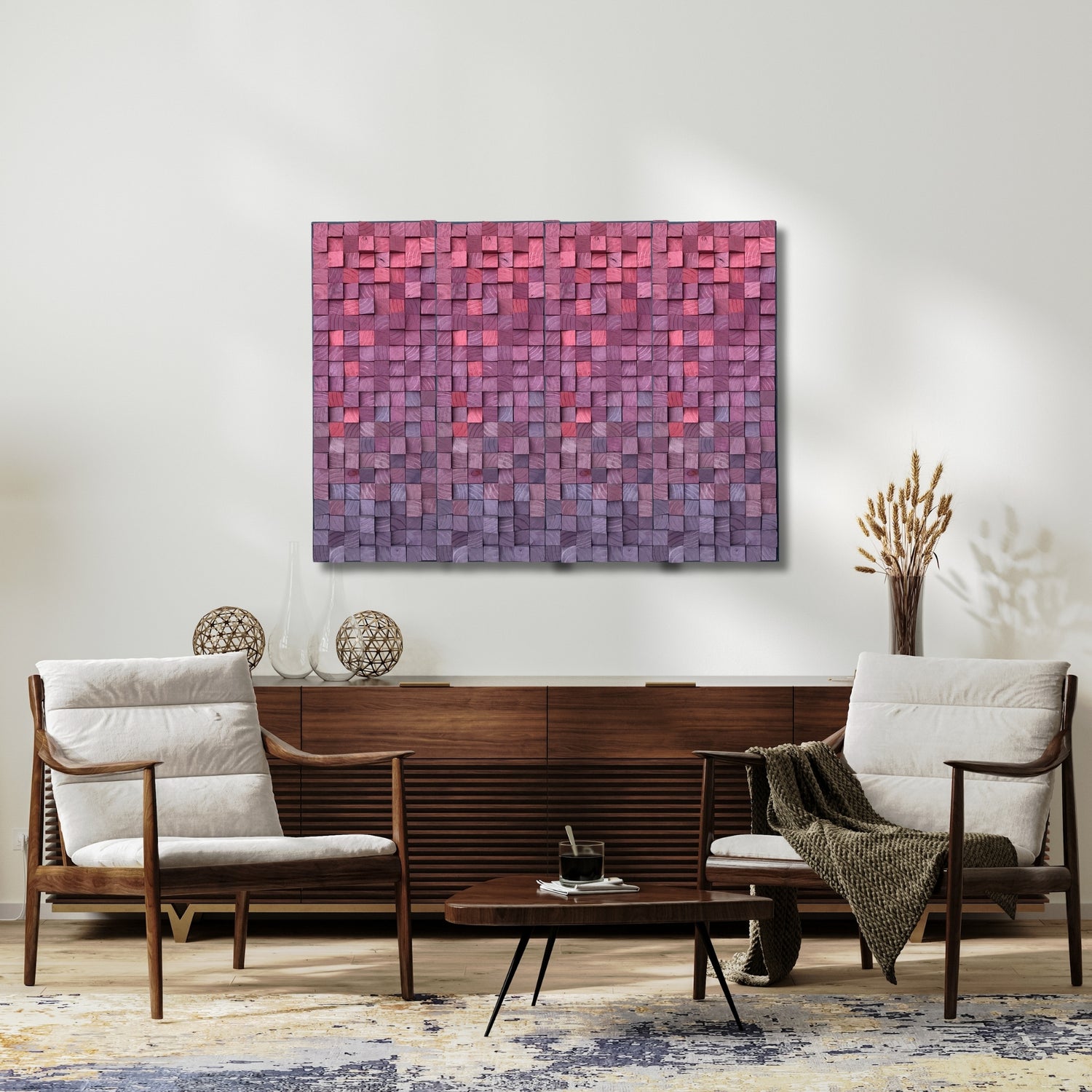 Handmade sculptural wood wall art featuring a painted mosaic in gradient tones of pink, magenta, and purple, displayed above a mid-century style wooden sideboard and flanked by modern armchairs in a bright, minimalist living space.