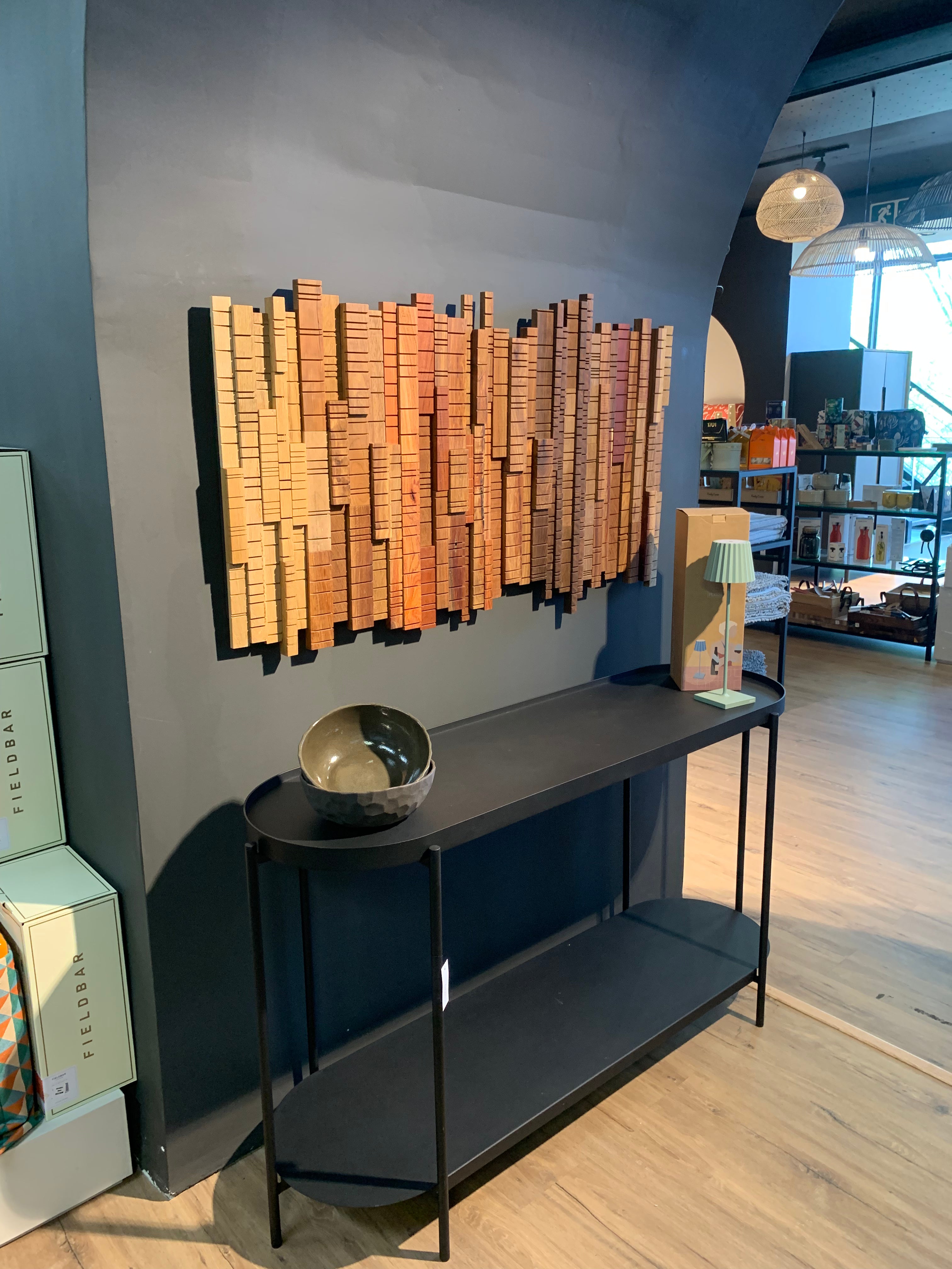 Sculptural wooden wall art from the “A Walk Through the Forest” collection, installed on a navy wall in a Johannesburg showroom. Warm tones and textured forms reflect natural forest layers.