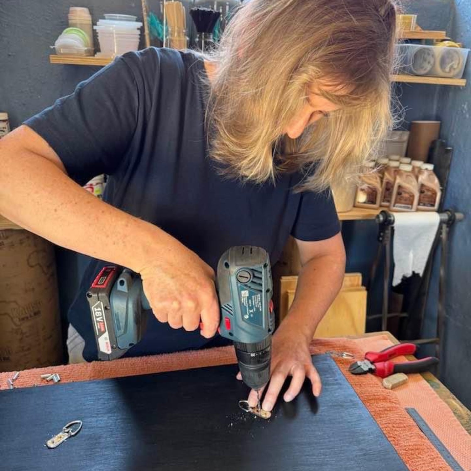Andrea attaching hanging hardware to a handmade wood wall art piece in her Johannesburg workshop studio