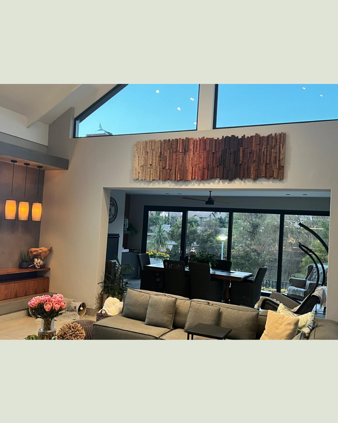 Custom handcrafted wooden wall art displayed above the open-plan dining and living area in a luxury contemporary home.