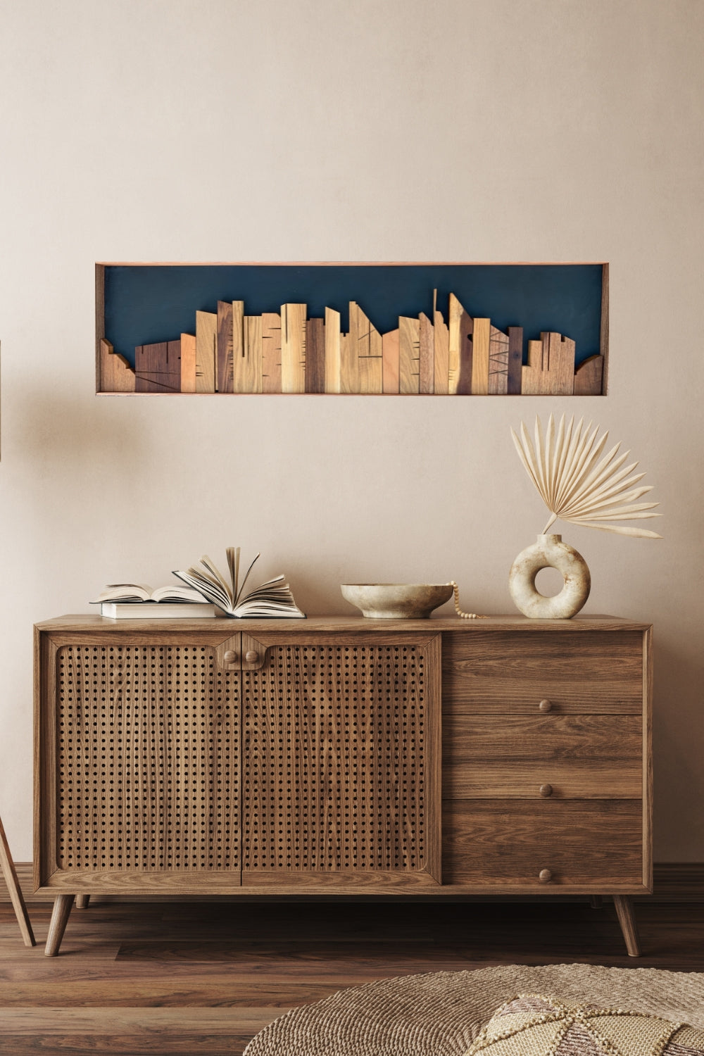 Cityscape wooden wall art displayed above a wooden sideboard in a warm modern interior.