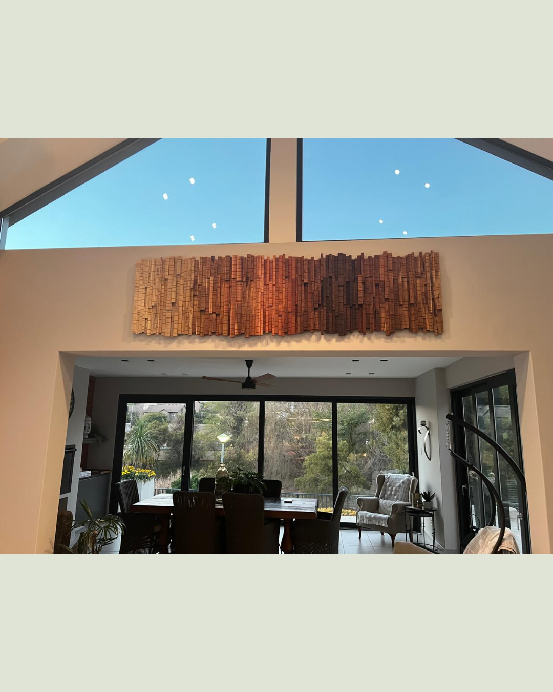 Finished custom wooden wall art installed above a wide doorway, complementing the home's modern architecture.