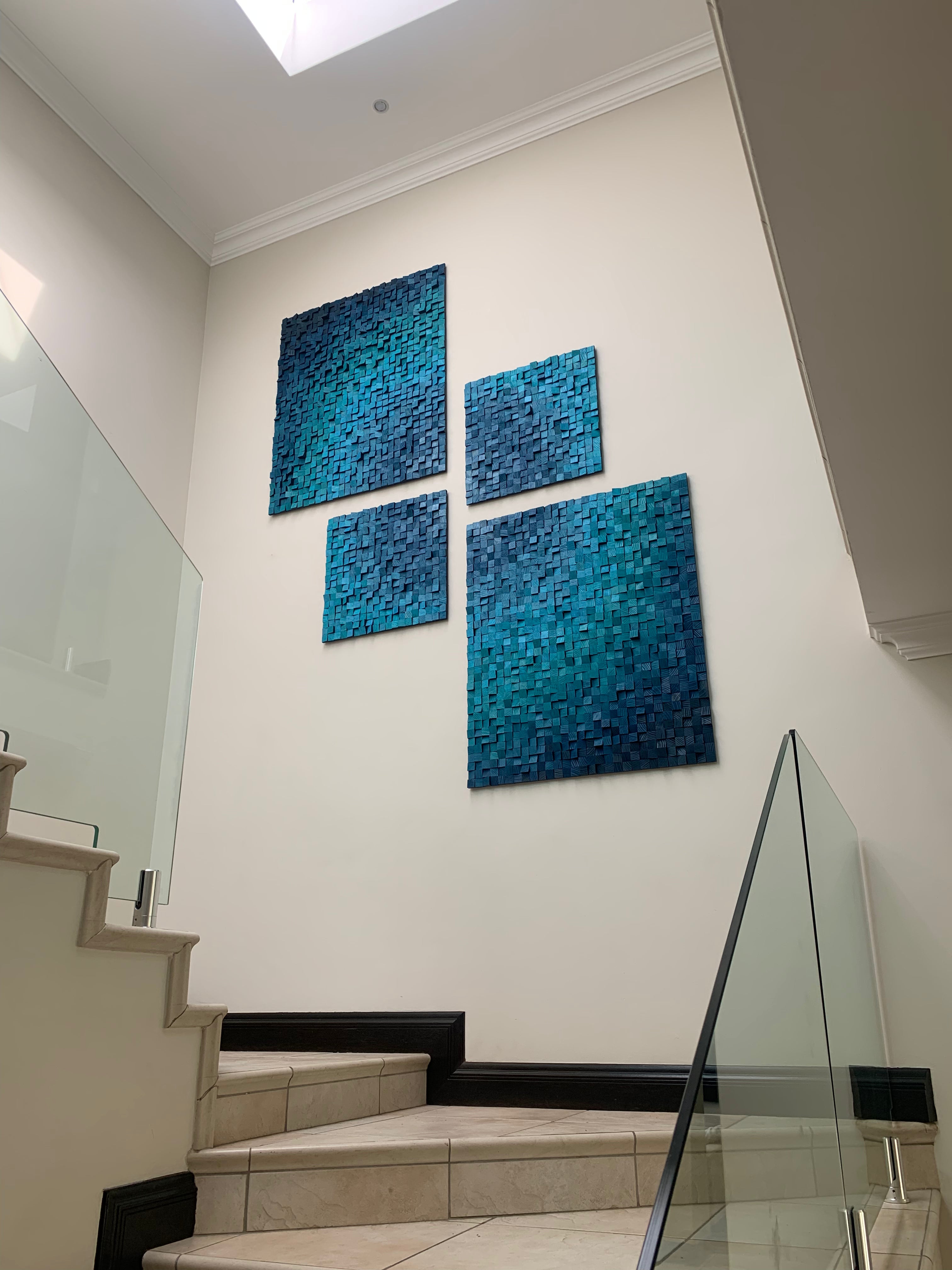Custom blue wooden wall art installation in stairwell – four sculptural panels arranged in a modern grid for House Platten”