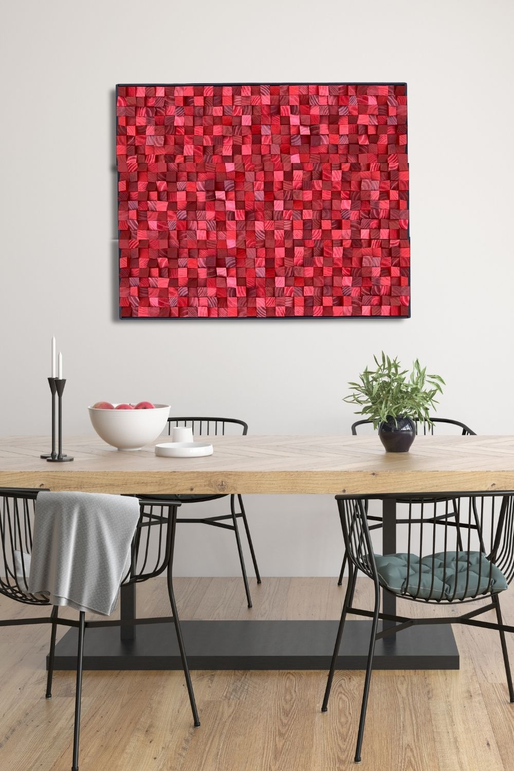 Textured red wood mosaic wall art displayed above a light wood dining table in a modern dining room with black wire chairs and soft neutral walls.